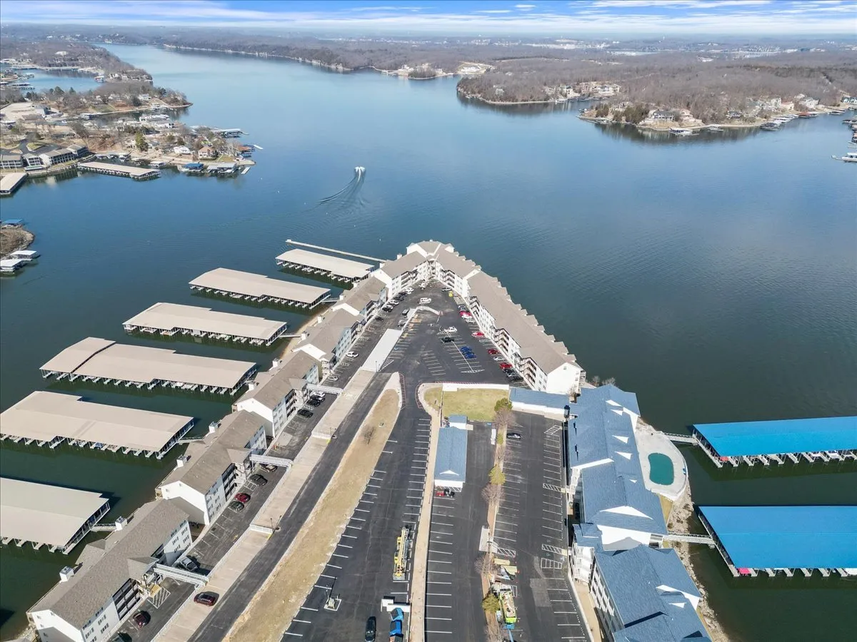 A bustling marina scene featuring docked boats, boathouses, and waterfront residential buildings. The image captures the energy of water activities and the neighborhood's vibrant, social setting.